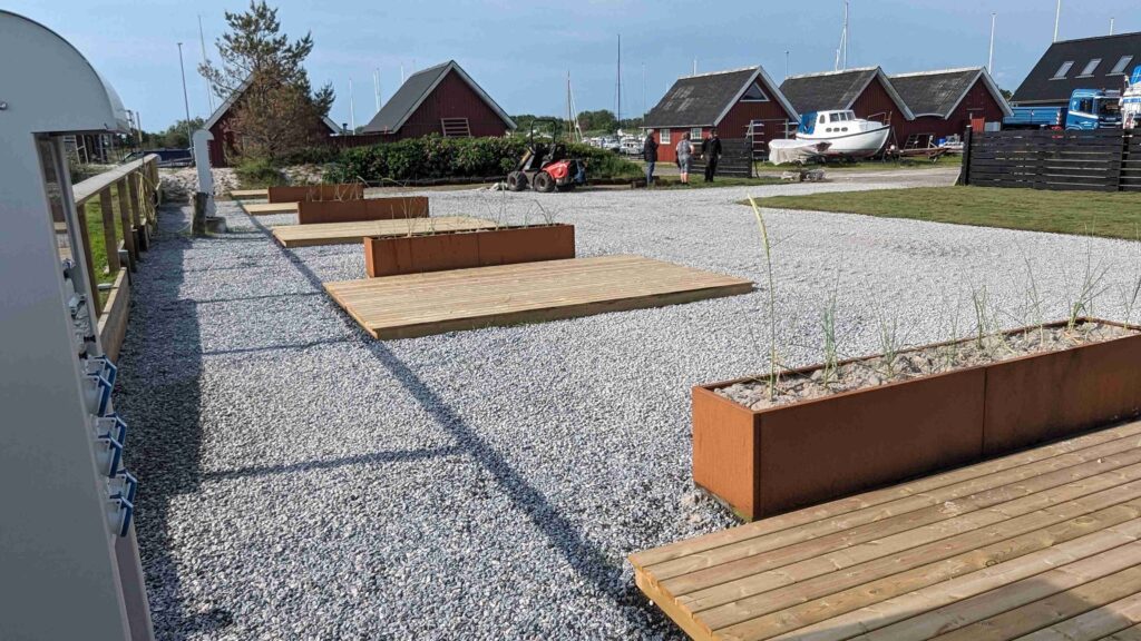 Stellplads med båse hvor der er en træterrasse til hver autocamper.